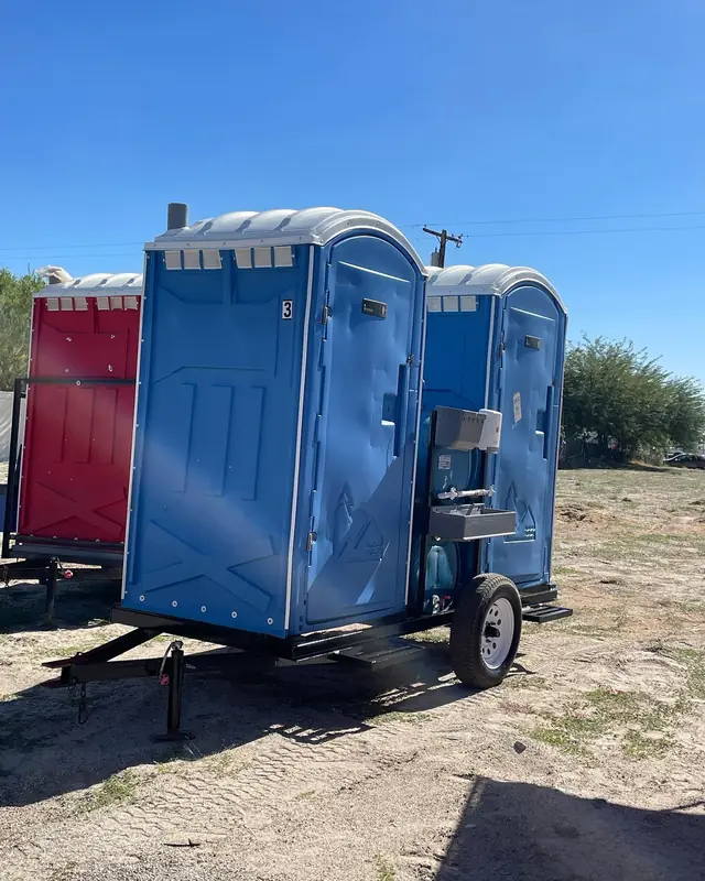 Blue portable toilets strapped upright on a delivery trailer
